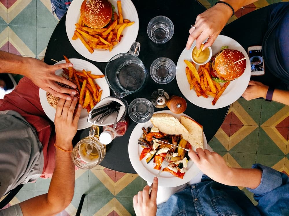 Manos alrededor de una mesa con comida